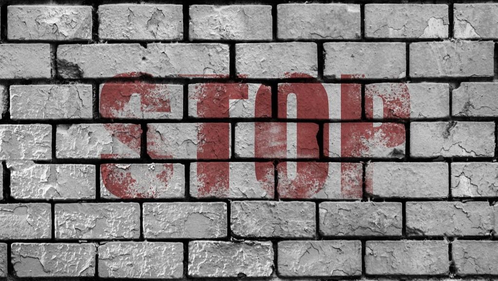 Graue Mauer mit roter Aufschrift 'Stop'