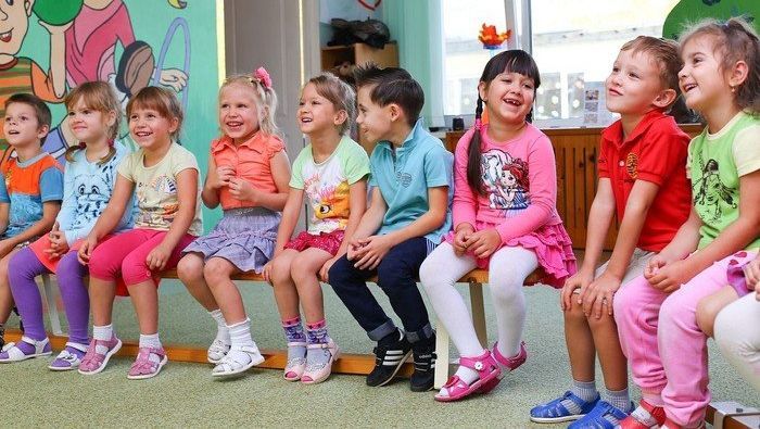Gruppe von Kindergartenkindern, auf einer Bank sitzend