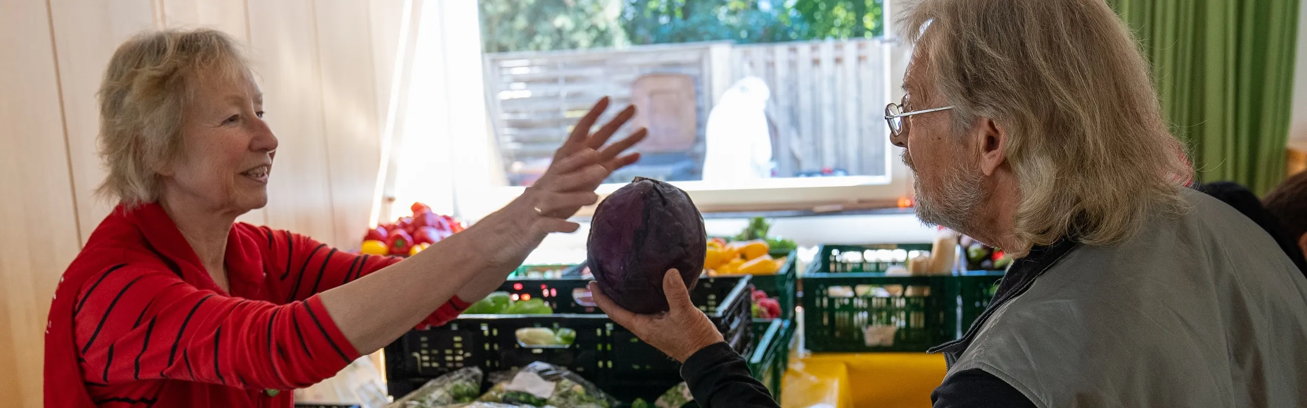 Eine Ehrenamtliche von Laib und Seele gibt einem Kunden einen Rotkohl