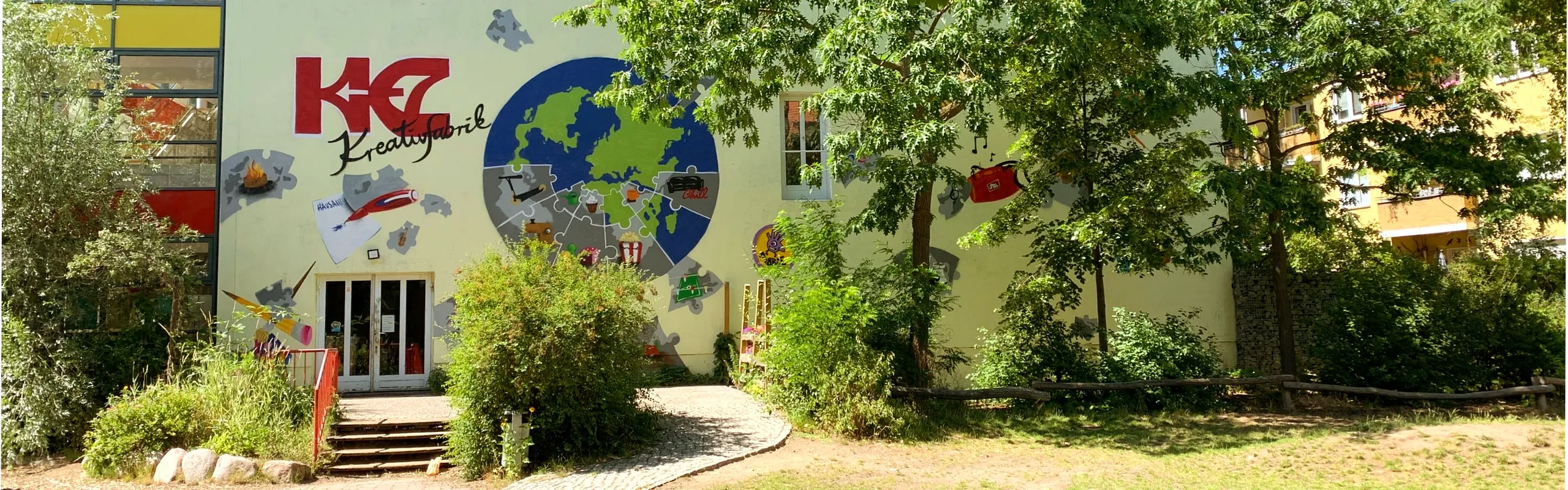 Haus der KreativFabrik von vorne, darauf eine Weltkugel